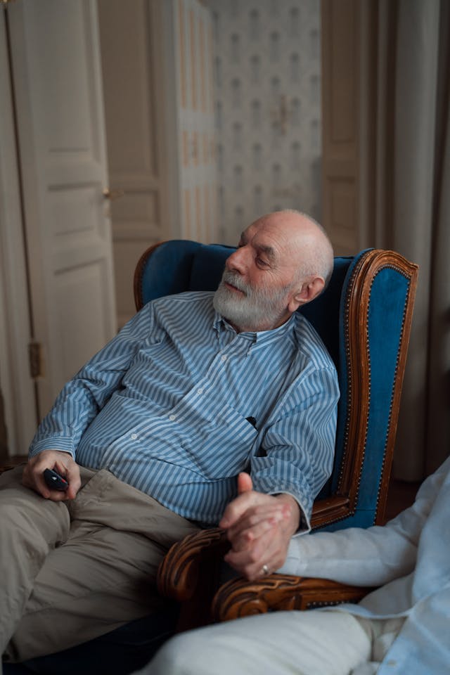 senior man in a chair holding hands with someone