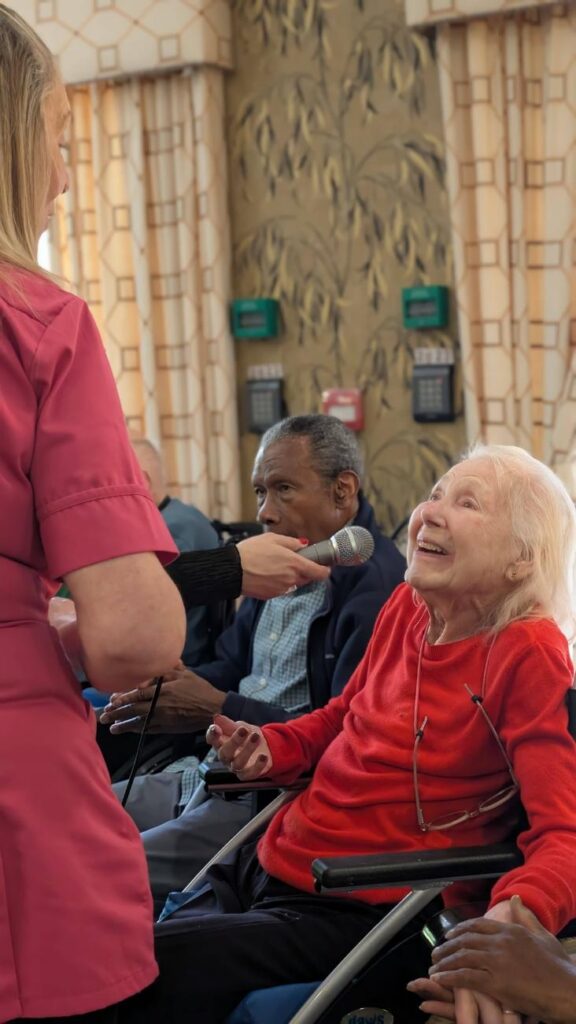 resident smiling and singing into microphone at care home 