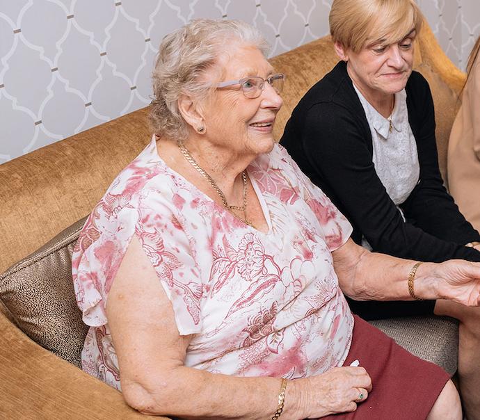 two older ladies sat on a yellow sofa