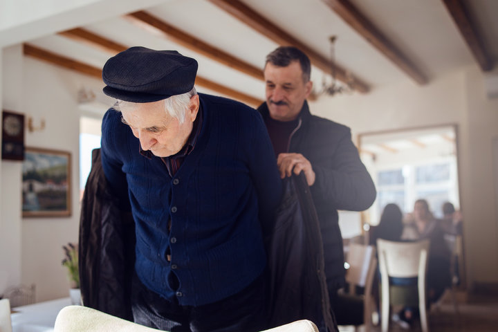 adult son helping his father to put on his coat